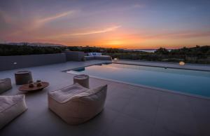 a swimming pool with a sunset in the background at White Grace - A Seductive World of Luxury in Pigi