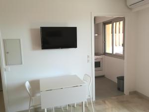 sala de estar con mesa blanca y TV en la pared en Sea Side Oceanides en Juan-les-Pins