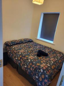 a bedroom with a bed with a flowered comforter and a window at Rest and Roam in Milltown