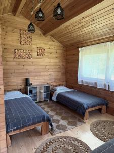 a bedroom with two beds in a wooden cabin at Akmens sala in Vecpiebalga