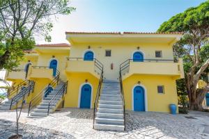 a yellow house with blue doors and stairs at Ammes Hotel in Svoronata