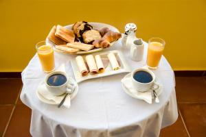 a table with a plate of bread and cups of orange juice at Ammes Hotel in Svoronata