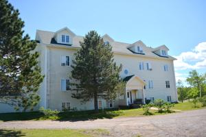 a large white house with trees in front of it at Cavendish Memotree Resort in Cavendish