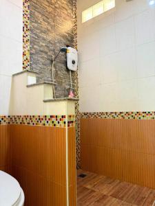 Un baño con inodoro y pared de azulejos. en Green Heaven Bungalow 1, en Nathon Bay