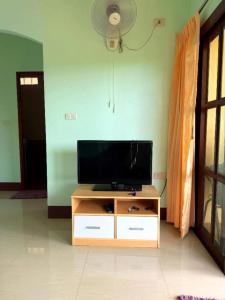 una sala de estar con un televisor de pantalla plana sobre un mueble en Green Heaven Bungalow 1, en Nathon Bay