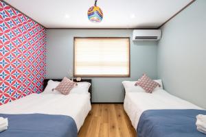 two beds in a room with a window at 長期ステイ歓迎 ポップ ディズニー風 TDR スカイツリー好アクセス 定員3名 東京駅10分 駐車場予約 送迎有 HOTEL DREAM MUSIC Tōyōchō japanese-pop in Tokyo