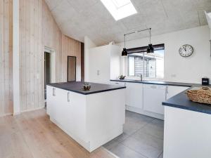 a kitchen with white cabinets and a clock on the wall at 5 star holiday home in Ringkøbing in Ringkøbing +38 photos