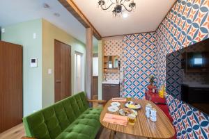 a living room with a table and a green couch at 長期ステイ歓迎 ポップ ディズニー風 TDR スカイツリー好アクセス 定員3名 東京駅10分 駐車場予約 送迎有 HOTEL DREAM MUSIC Tōyōchō japanese-pop in Tokyo