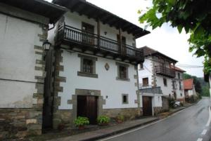 a white building with a balcony on a street at Casa Rural Janet in Izalzu