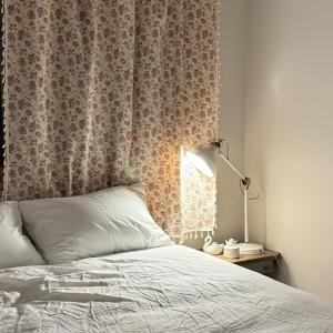 1 dormitorio con 1 cama con cortina y lámpara en Magnolia Wonju branch, en Wonju