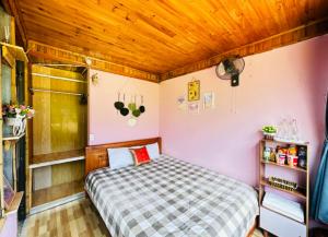 a small bedroom with a bed and wooden ceilings at Terrace House Tả Van in Sapa