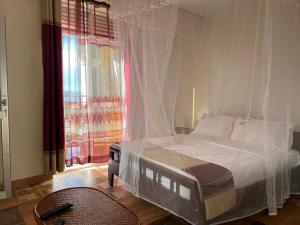 a bedroom with a bed with a mosquito net at Hotel Royal Nest Entebbe in Entebbe