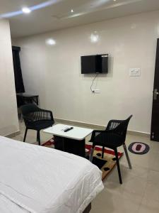 a room with a bed and two chairs and a tv at Hotel Abhimanyu Villa in Hyderabad