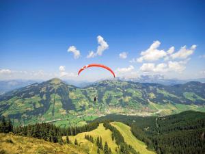 een persoon die met een parachute in de lucht boven een berg zweeft bij Apartment in Kirchberg near Ski Bus in Kirchberg in Tirol