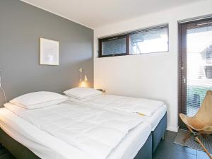 a bedroom with a large white bed with a chair at 5 star holiday home in Bogense in Bogense