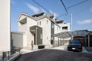a white house with a car parked in a driveway at Fukuoka Airport 6 in Shime