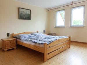 a bedroom with a wooden bed and two windows at Villa Hochwald Familienhaus in Geisfeld +22 photos