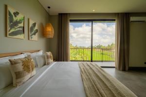 a bedroom with a large bed with a large window at Renjana Villas in Ubud