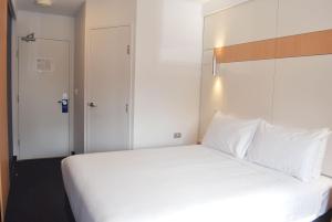 a bedroom with a large bed with white pillows at ibis Budget - Gosford in Gosford +17 photos