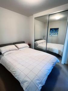 a bedroom with a large white bed and a mirror at Melbourne Double Cozy in Melbourne