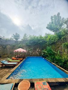 a swimming pool with chairs and an umbrella at Uluwatu Hill House in Uluwatu