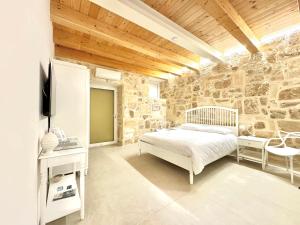 a bedroom with a bed and a stone wall at Amurusa Room in Noto