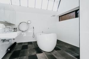 a bathroom with a white tub and a sink at Alkina Lodge Yani in Wattle Hill +35 photos