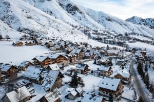a village covered in snow with mountains in the background at Appartement Haut de Gamme neuf avec terrasse de 60m2 plein sud avec Jacuzzi- 8 personnes in Saint-Sorlin-dʼArves