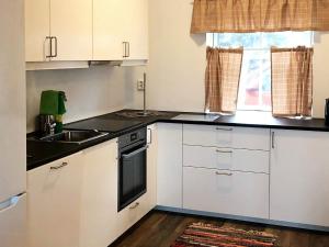 a kitchen with white cabinets and a sink and a window at 6 person holiday home in Kverva in Dyrvik