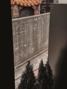 a wall with two trees in front of a building at Here Hotel 宅這兒私宅-台南B宅 in Tainan