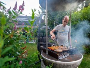a man is cooking meat on a grill at Peaceful Garden Hideaway in Cerfontaine