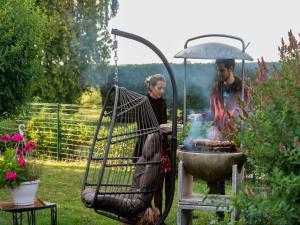a man and a woman cooking food on a grill at Peaceful Garden Hideaway in Cerfontaine
