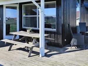 a wooden picnic table and a bench on a porch at 6 person holiday home in Lemvig-By Traum in Trans
