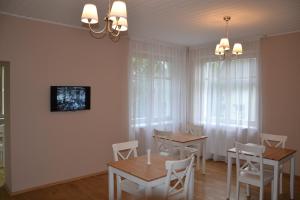 a dining room with white chairs and tables and windows at Liepa in Šilutė