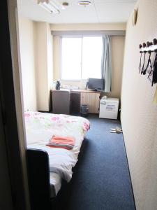 a small room with a bed and a window at Asahikan in Kofu