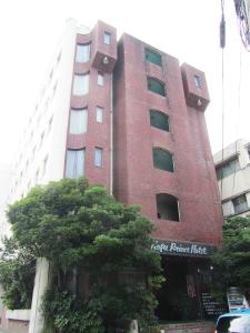 甲府的住宿－阿薩黑坎經濟型酒店，一座高大的红砖建筑,前面有一棵树