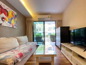 a living room with a couch and a television at The Title Rawai Aparthotel by HSS in Rawai Beach