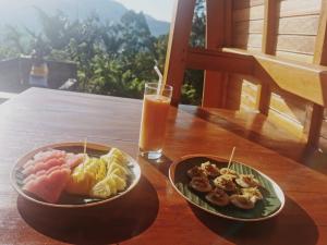 a table with two plates of food and a glass of orange juice at Kastawa Villa in Sidemen