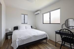 a bedroom with a bed and a desk and two windows at Fukuoka Airport 8 in Shime