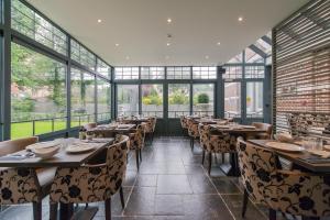 a dining room with tables and chairs and windows at Boutique Hotel Huys van Steyns in Tongeren