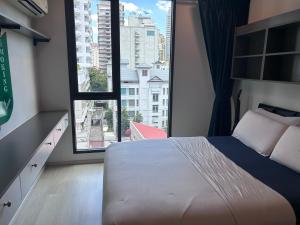 ein Schlafzimmer mit einem Bett und einem großen Fenster in der Unterkunft Sukhumwit Soi 10 at VENiO in Klong Toi + 17 Fotos