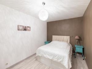 a bedroom with a white bed and a blue table at Tranquil Garden Retreat by the Sea in Englesqueville-la-Percée
