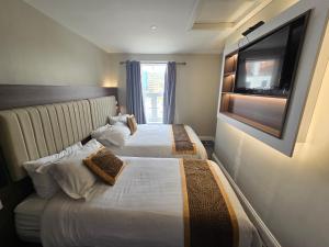 two beds in a hotel room with a tv on the wall at Double bedroom studios in Dublin
