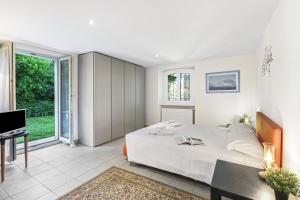 a white bedroom with a bed and a television at Oasi Panoramica con piscina - Happy Rentals in Aldesago