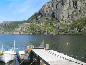 a dock with a boat in the water next to a mountain at 6 person holiday home in Bøstad-By Traum in Tangstad
