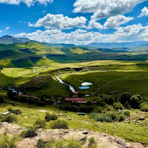 a view of a valley with a farm in a field at Tsoelike River Lodge in Sehlabathebe