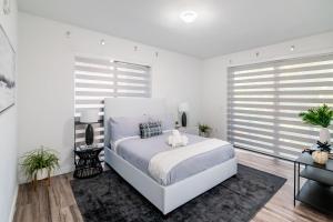a white bedroom with a large white bed and windows at 2BR Miami Condo - Near Marina & Attractions in Miami