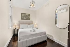 a white bedroom with a white bed and a mirror at Millers Point Retreat 5 Min Walk to Barangaroo in Sydney