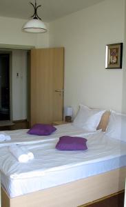 a large white bed with two purple pillows on it at Two-Bedroom Apartment Donika in Tsarevo