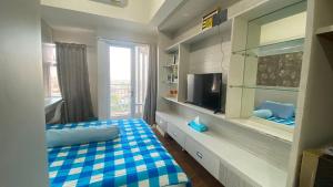 a bedroom with a bed and a tv in a room at Apartemen VidaView Unit AT19P By Millpro in Pampang